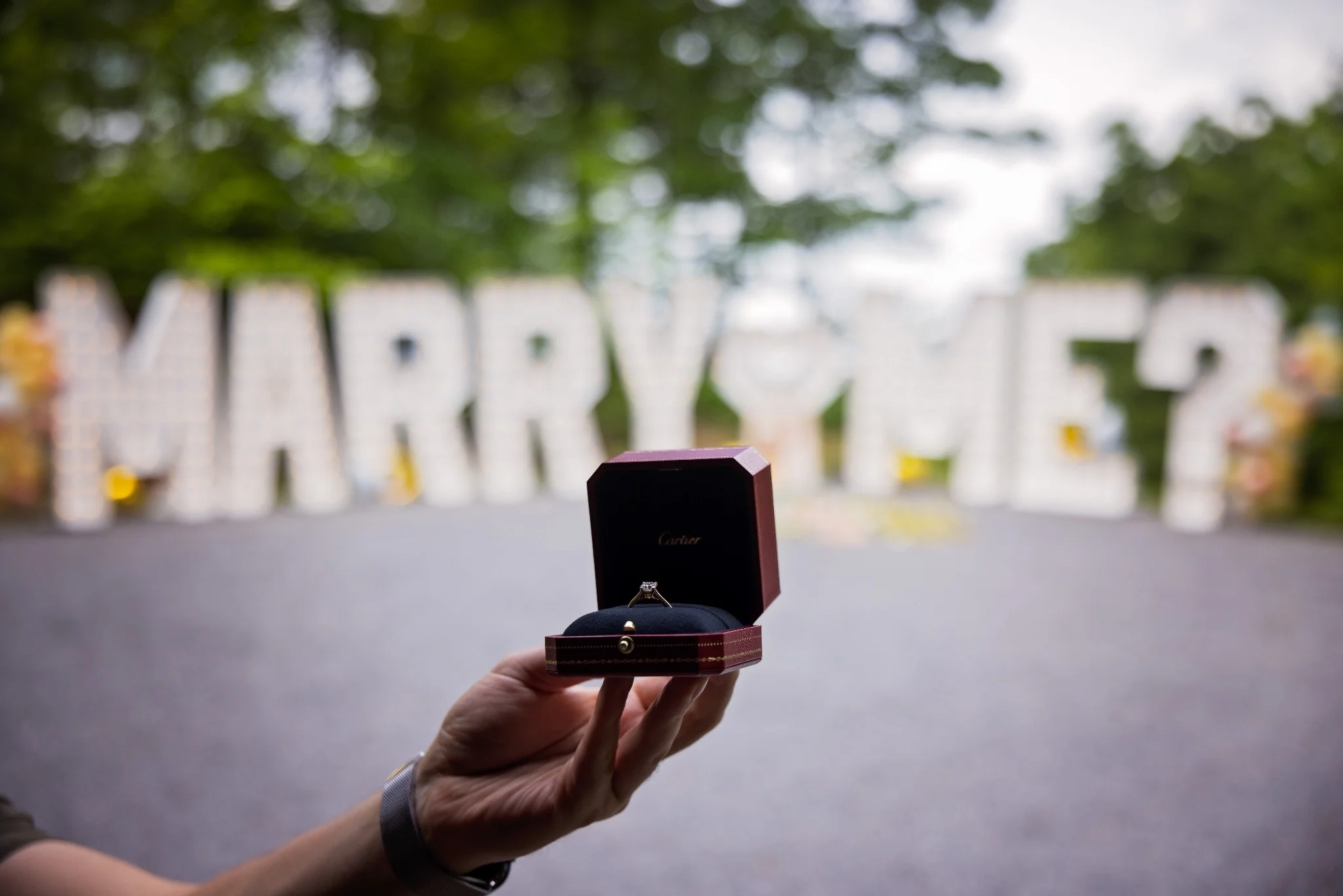 A ring held in front of 7ft tall Marry Me Marquee Letters in Nashville, TN