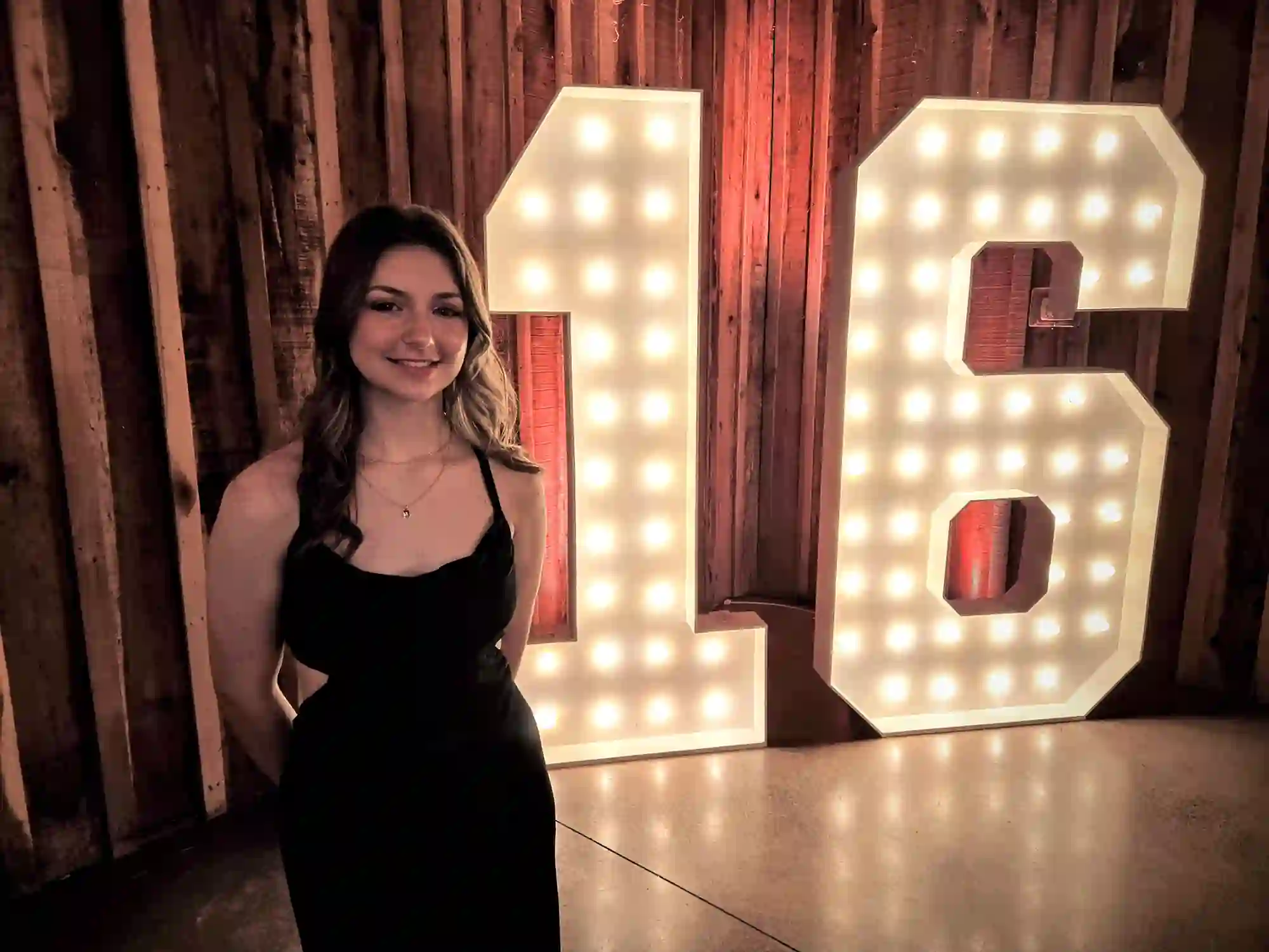 Sweet 16 birthday girl standing in front of giant "16" marquee numbers at Sacred Stone barn in Fayetteville, TN