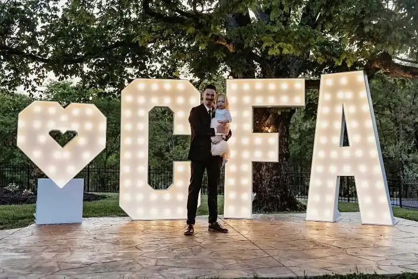 Couple standing in front of illuminated CFA marquee letters at an outdoor Chick-fil-A corporate event in Hendersonville, TN
